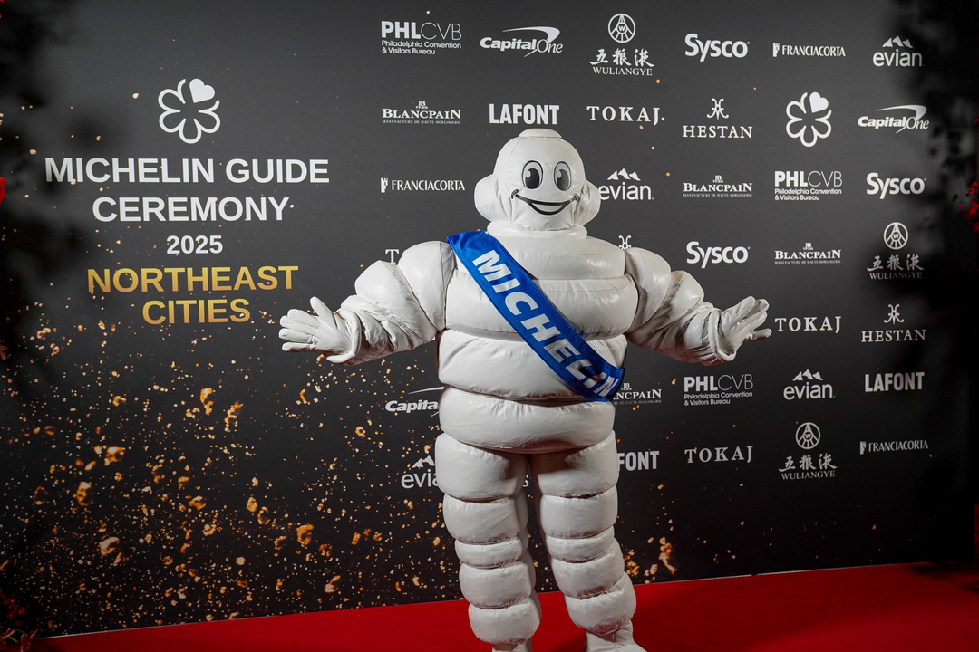 The michelin man stands in front of a MICHELIN Guide step and repeat