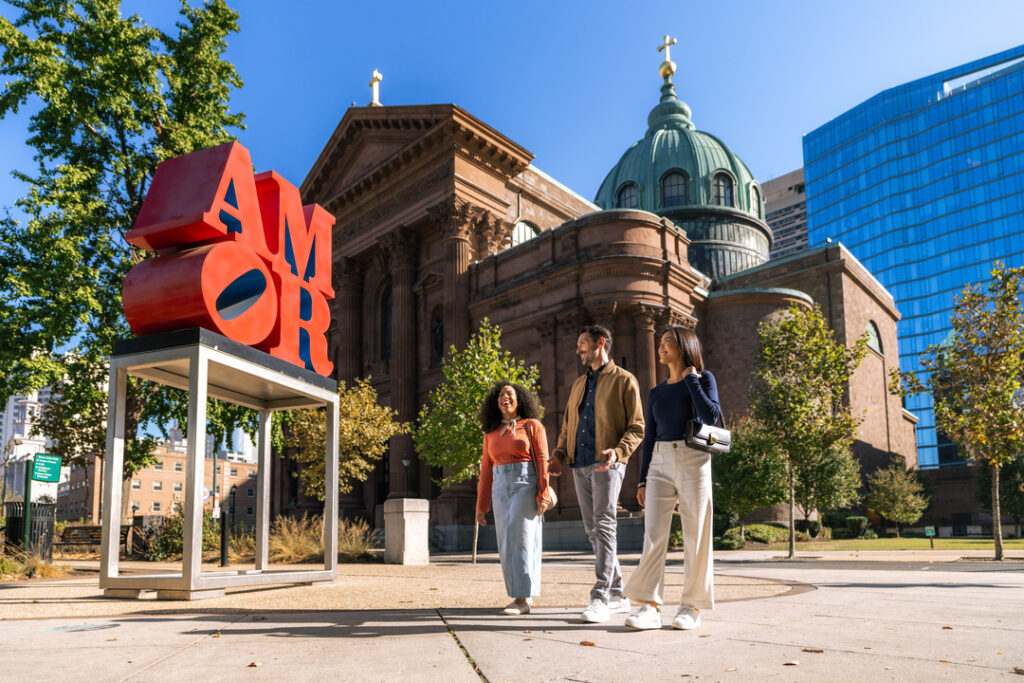 Two people walk by the Philadelphia AMOR statue