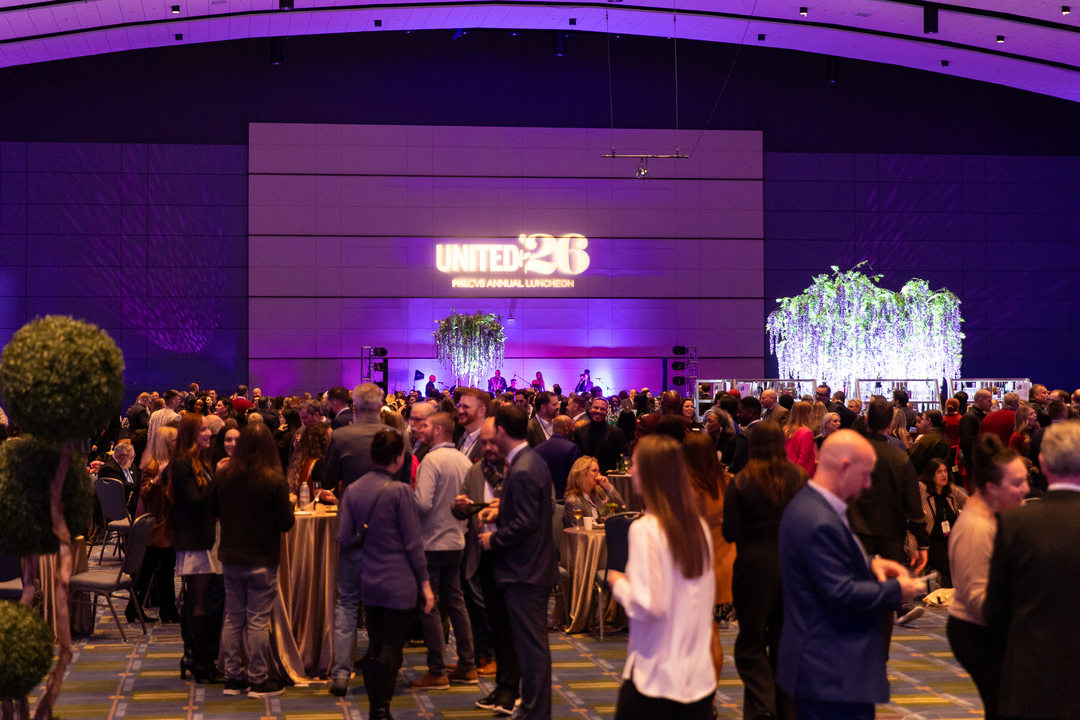 A room lit with purple lighting, full of people gathering for an event.