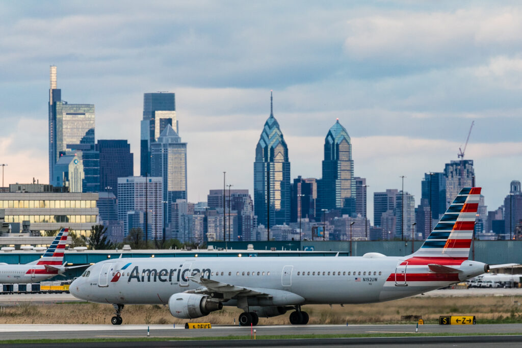 An American airlines airplane in front of the city skyline.
