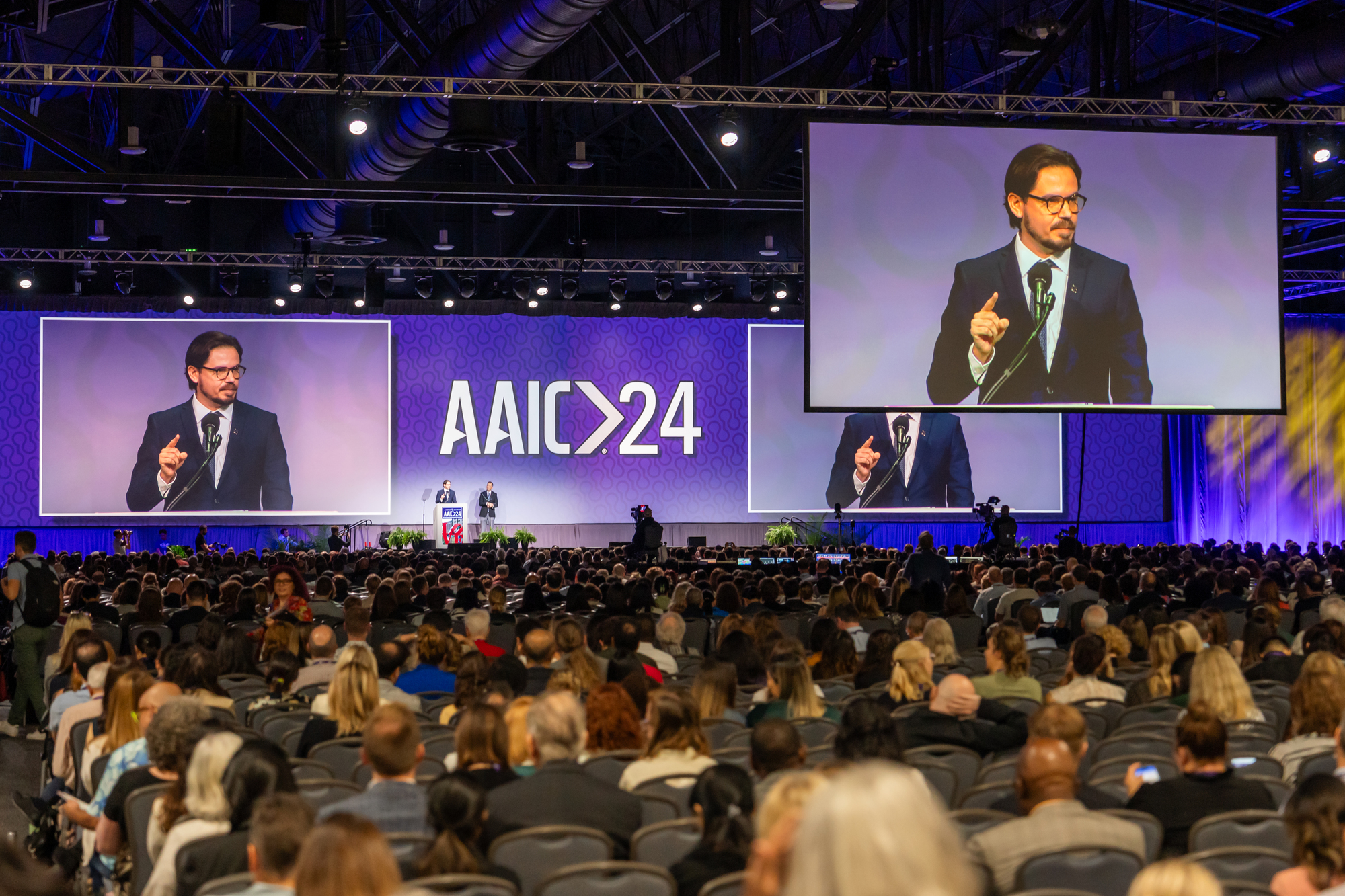 A man in a suit is talking in front of a large crowd at the Pennsylvania Convention Center.