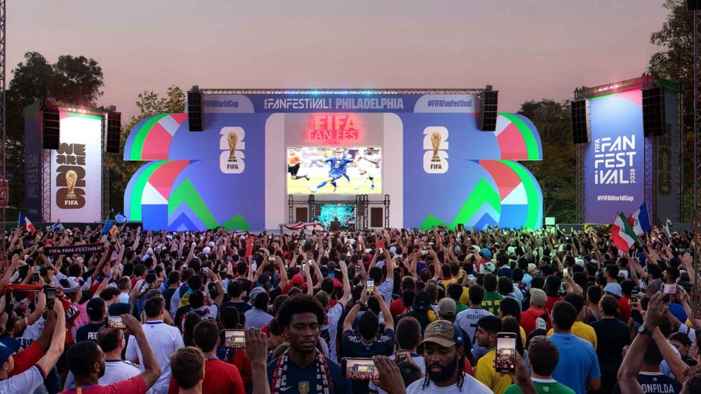 A large crowd gathers in front of a stage airing the World Cup games
