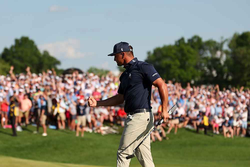 A golfer walks in front of a crowd, fist clutched in victory