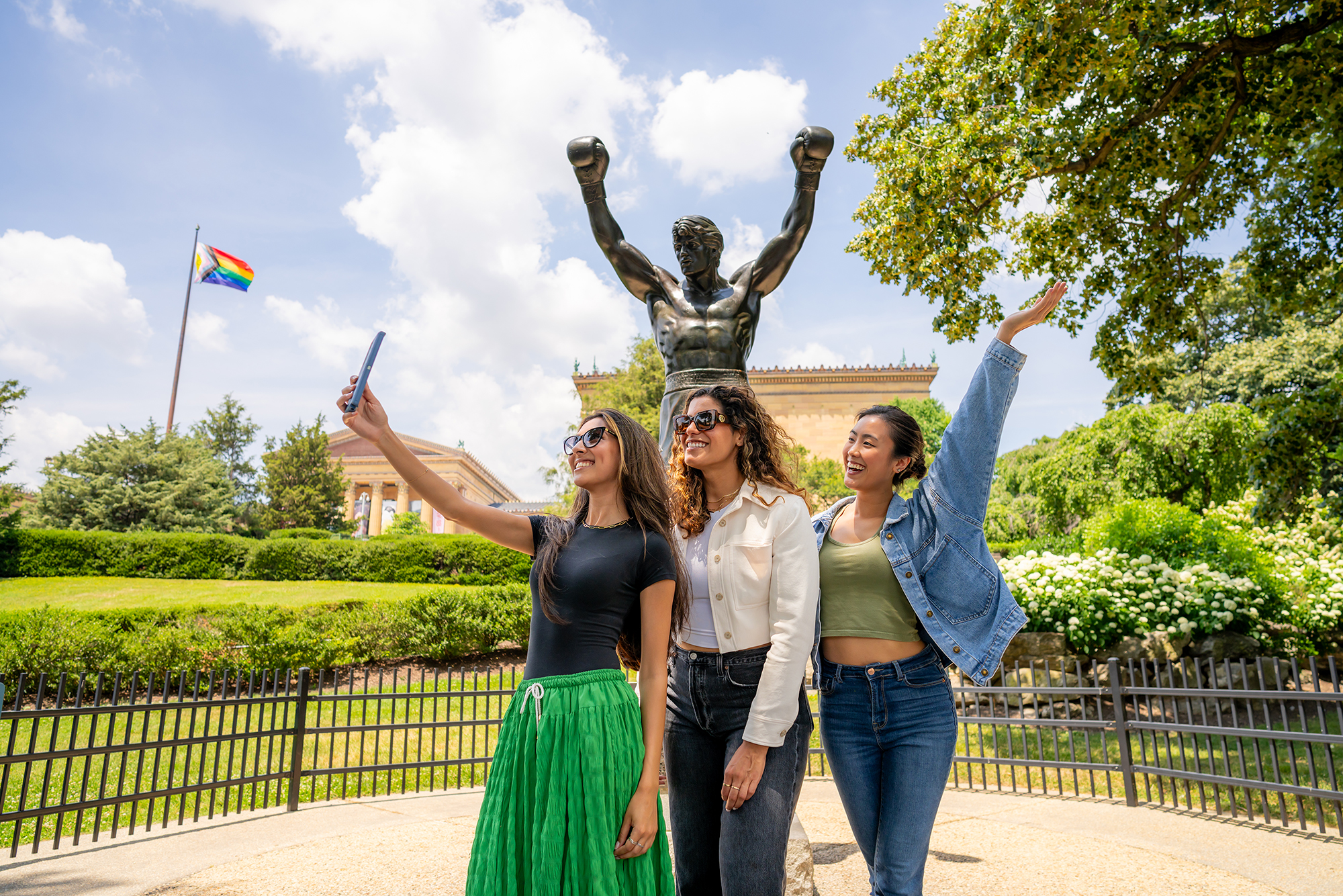 Three people pose for a selfie in front of the Rocky Statue
