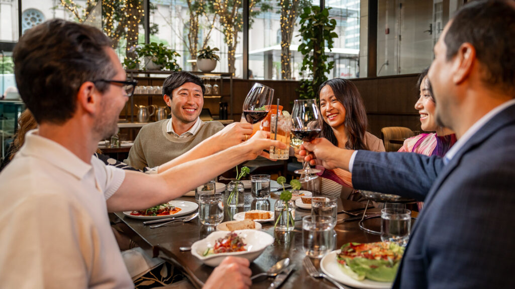 A group of diners cheers wine glasses over a meal at Vernick Fish.