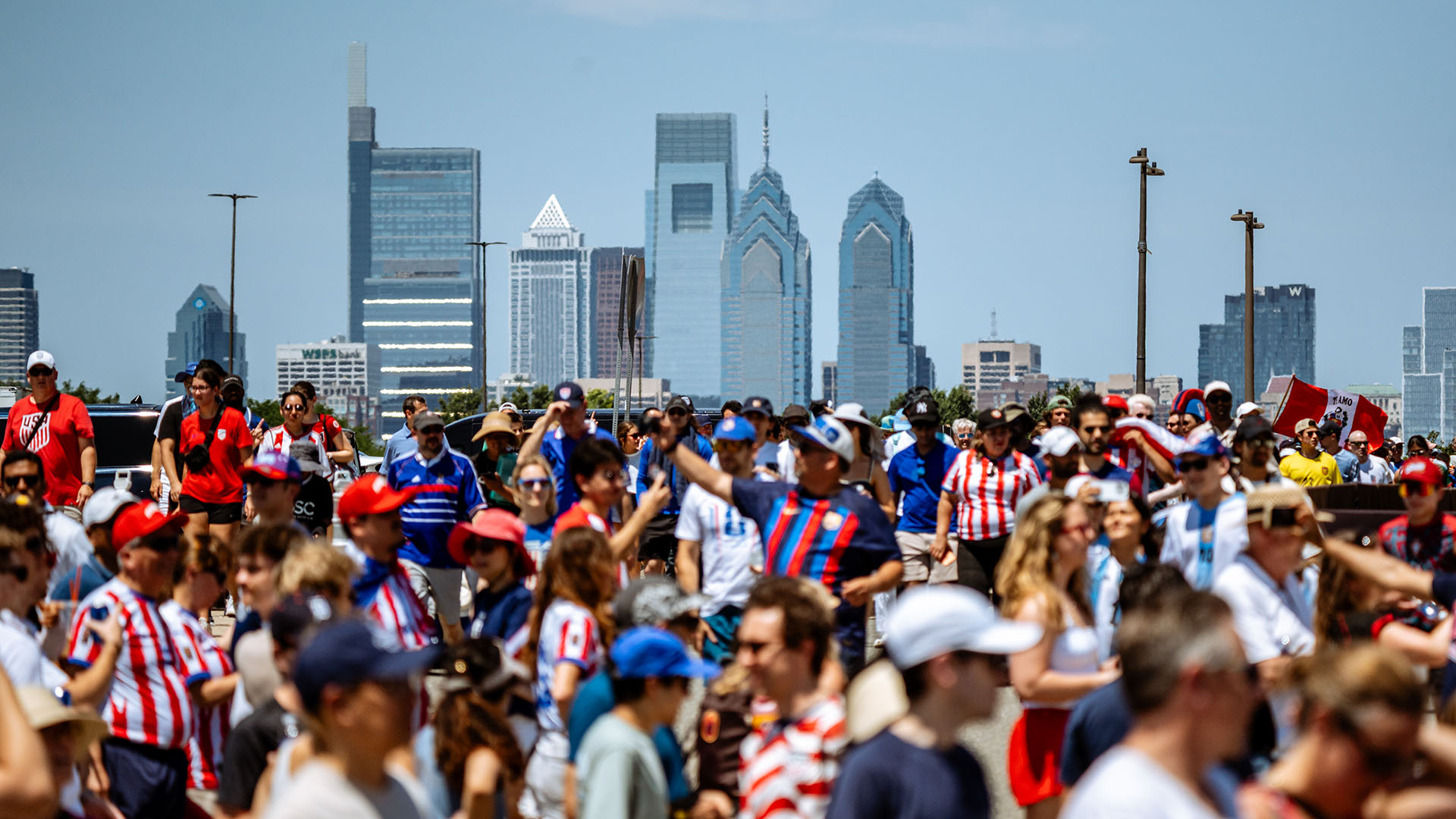 A large group of people gather in front of the Philadelphia city skyline for the World Cup event.