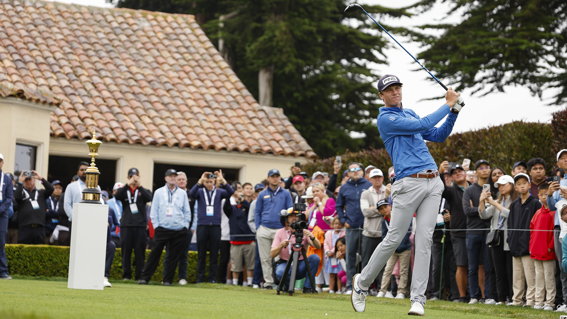 A golfer takes a swing in front of a crowd