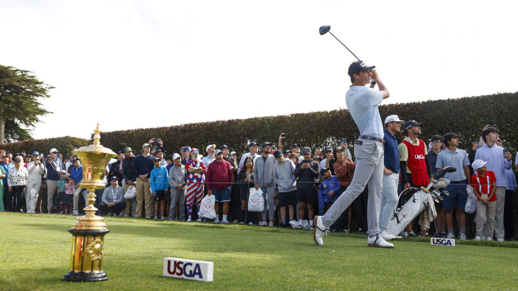 A golfer takes a swing in front of a crowd