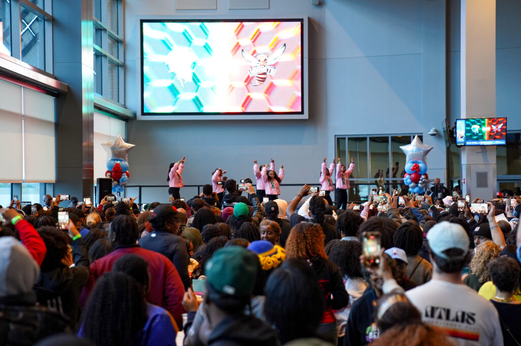Women dancing on a stage in front of a large crowd.