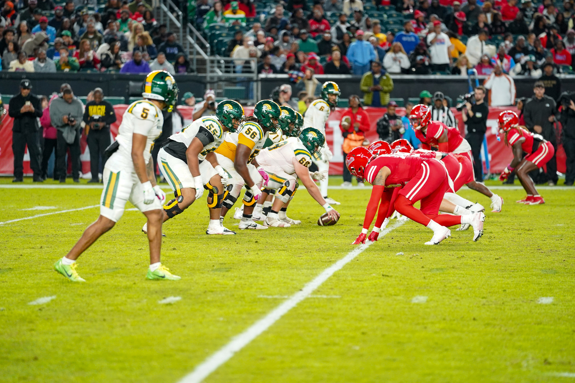 Football players in white and red uniforms in position on a field before the start of a play.